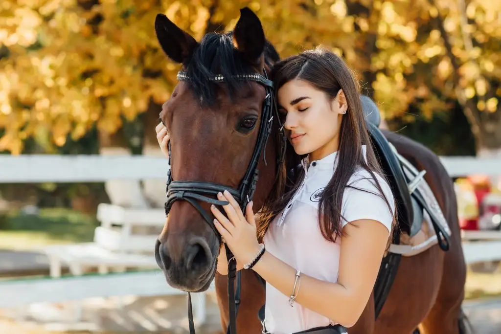 Junge hübsche Frau lehnt an einem Pferd