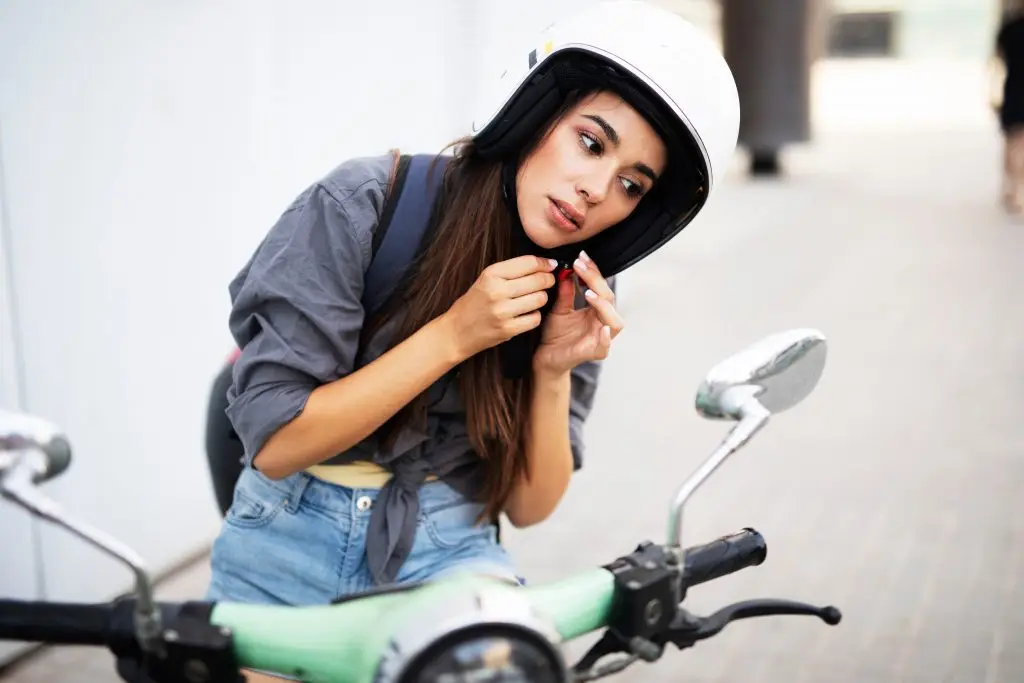 Schöne junge Frau mit Helm auf einem Moped